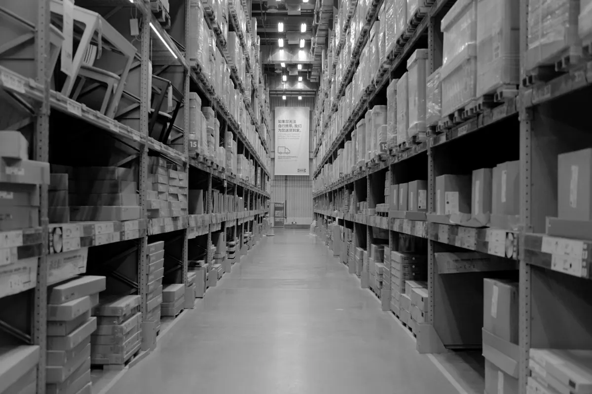 A long warehouse aisle between tall shelves stacked with boxes